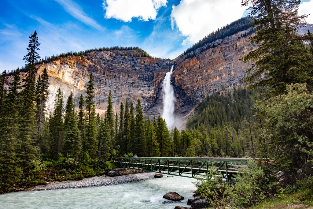 Image shows footbridge in the foreground leading to Takakkaw Falls in Yoho National Park