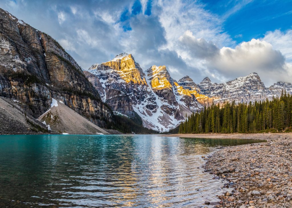 Pano of Moraine Lake on the shoreline at Sunrise as the Sun illuminates the Valley of Ten Peaks