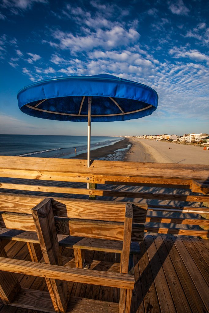 A blue umbrella overlooks Surfside beach at sunrise.